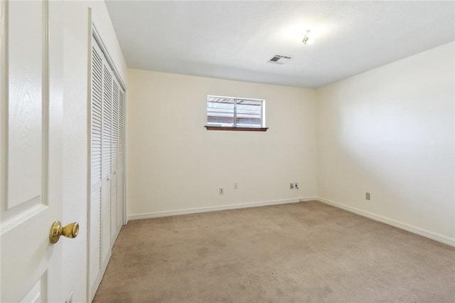 unfurnished bedroom with light colored carpet and a closet