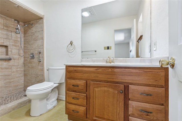 bathroom with toilet, vanity, and tiled shower