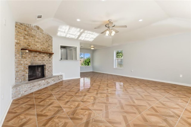 unfurnished living room with baseboards, visible vents, a ceiling fan, a brick fireplace, and recessed lighting