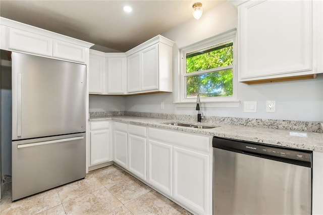 kitchen featuring light stone countertops, white cabinetry, stainless steel appliances, and a sink