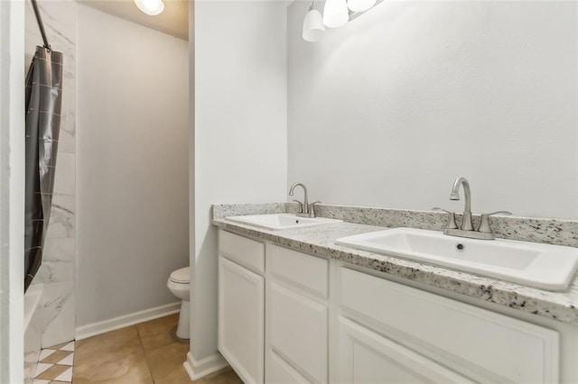 full bath with toilet, double vanity, a sink, and tile patterned floors