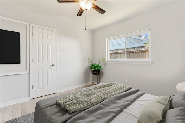 bedroom with light tile patterned floors, ceiling fan, and baseboards