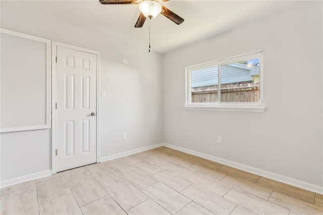 spare room with ceiling fan and baseboards