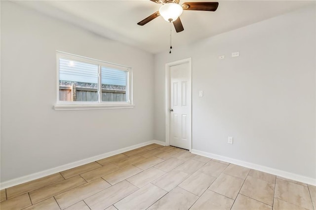 spare room with ceiling fan and baseboards