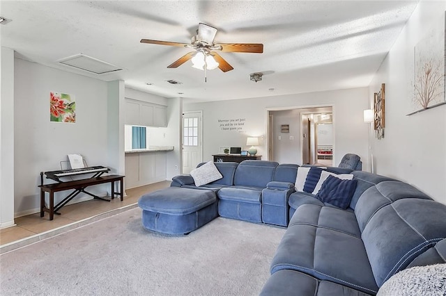 living room with a textured ceiling, carpet floors, and ceiling fan