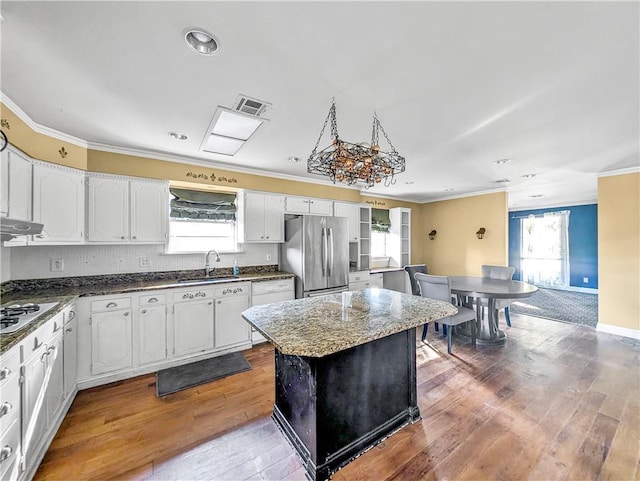 kitchen with a center island, white cabinetry, light hardwood / wood-style floors, sink, and stainless steel fridge