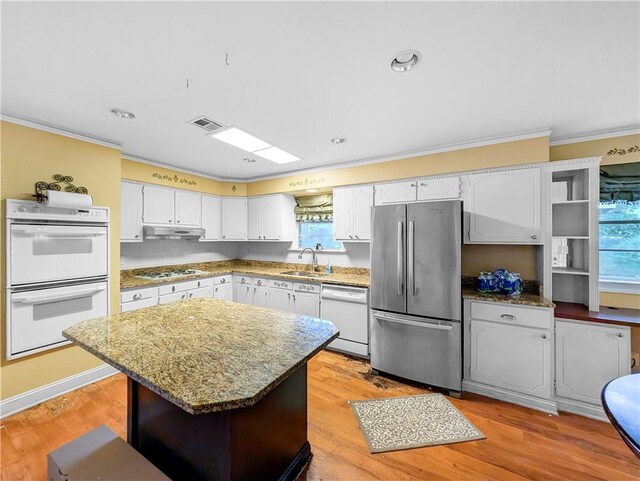 kitchen featuring white cabinetry, light hardwood / wood-style floors, a center island, white appliances, and sink