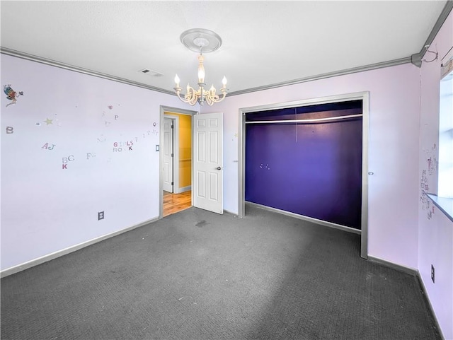 unfurnished bedroom featuring dark carpet, a closet, ornamental molding, and a chandelier