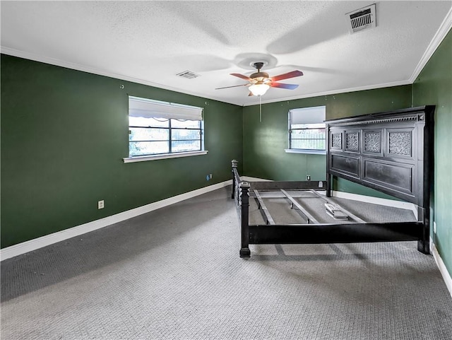 unfurnished bedroom featuring ceiling fan, carpet floors, multiple windows, and a textured ceiling