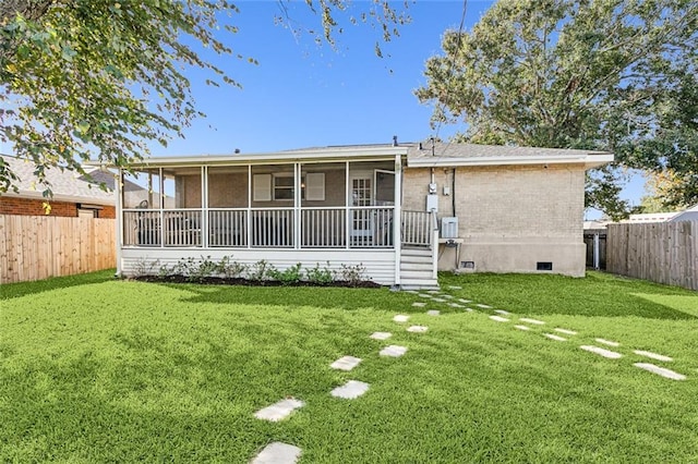 back of property featuring a sunroom and a lawn