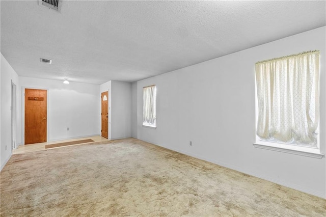 spare room featuring light carpet and a textured ceiling