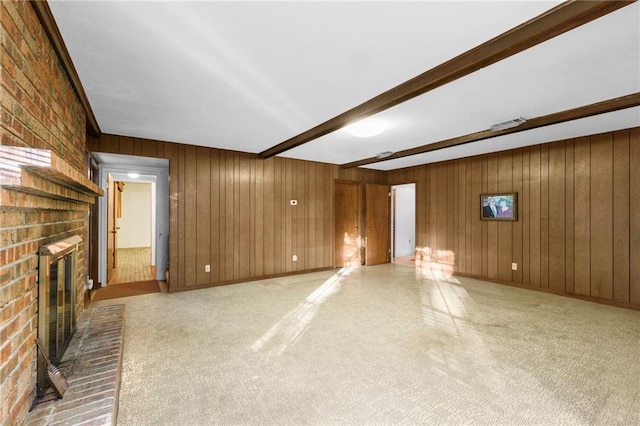 unfurnished living room with wooden walls, beamed ceiling, brick wall, and a brick fireplace