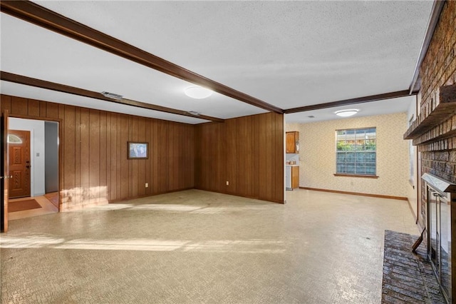 unfurnished living room with beamed ceiling, a textured ceiling, a fireplace, and wood walls