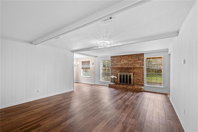 unfurnished living room featuring visible vents, dark wood-style floors, beamed ceiling, a fireplace, and a chandelier