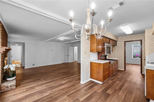 kitchen with visible vents, dark wood finished floors, brown cabinetry, light countertops, and a fireplace