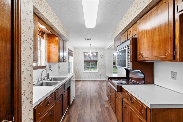 kitchen with pendant lighting, light countertops, brown cabinetry, a sink, and wallpapered walls