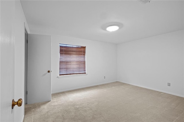 unfurnished room featuring light carpet and baseboards