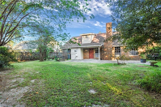 back of property featuring a patio area, a chimney, fence, and a yard