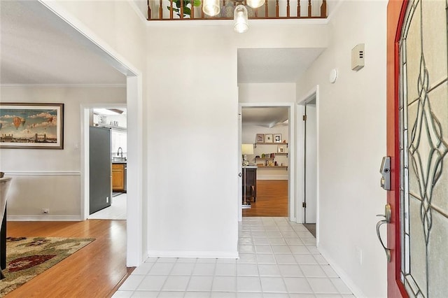 entrance foyer featuring crown molding, sink, and light wood-type flooring