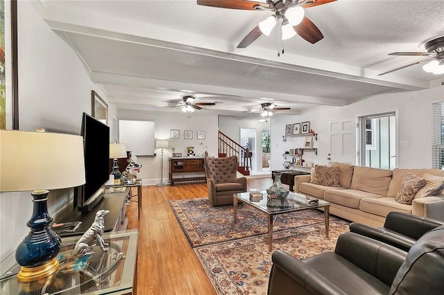 living room featuring light hardwood / wood-style floors, a textured ceiling, and beam ceiling