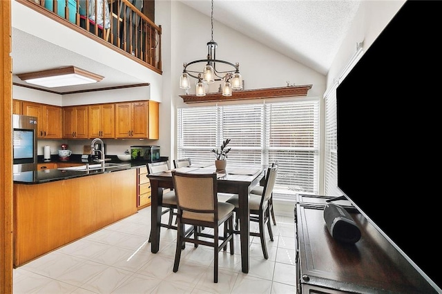 dining space with high vaulted ceiling, a textured ceiling, sink, and a chandelier