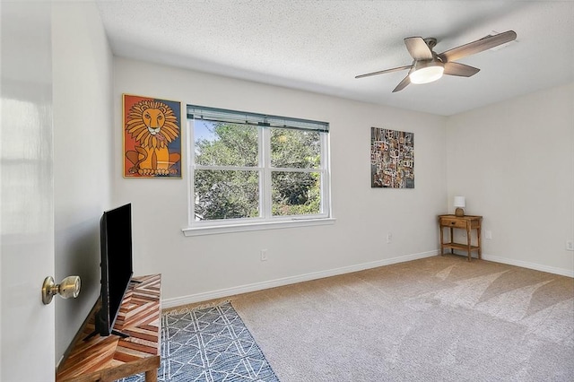 carpeted spare room with a textured ceiling and ceiling fan