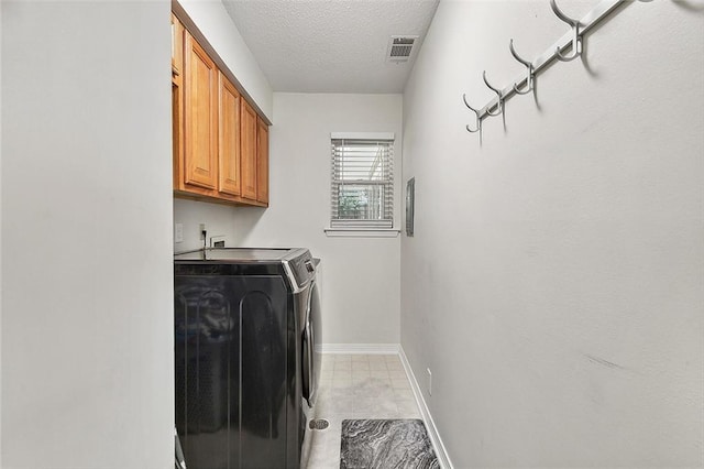 washroom featuring cabinets, a textured ceiling, and washing machine and dryer