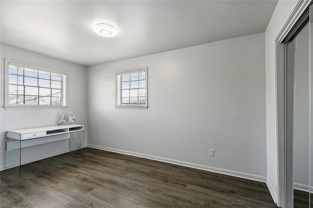 unfurnished bedroom featuring a closet, multiple windows, and dark hardwood / wood-style flooring