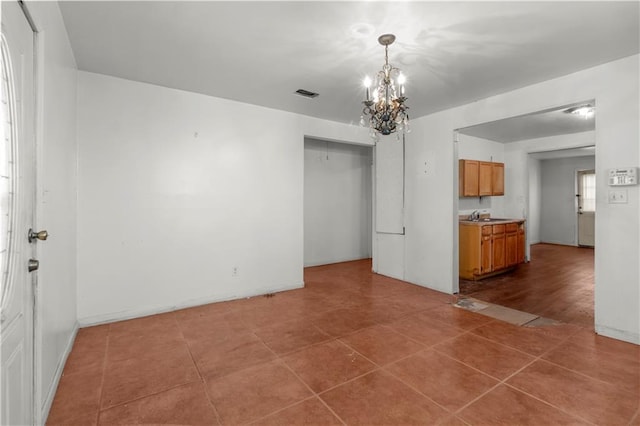 tiled spare room with sink and a chandelier