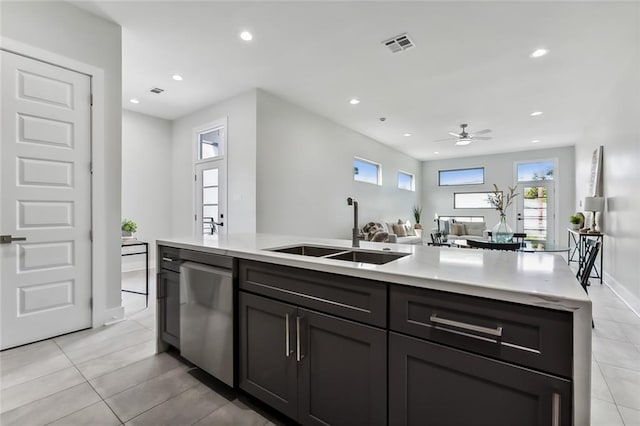 kitchen featuring stainless steel dishwasher, sink, a kitchen island with sink, and light tile patterned floors