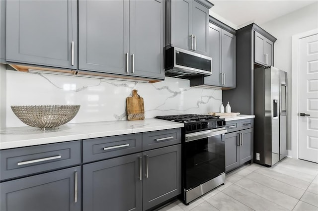610 David St, New Orleans, LA 70119 - kitchen with stainless steel appliances, backsplash, light stone counters, gray cabinetry, and light tile patterned flooring