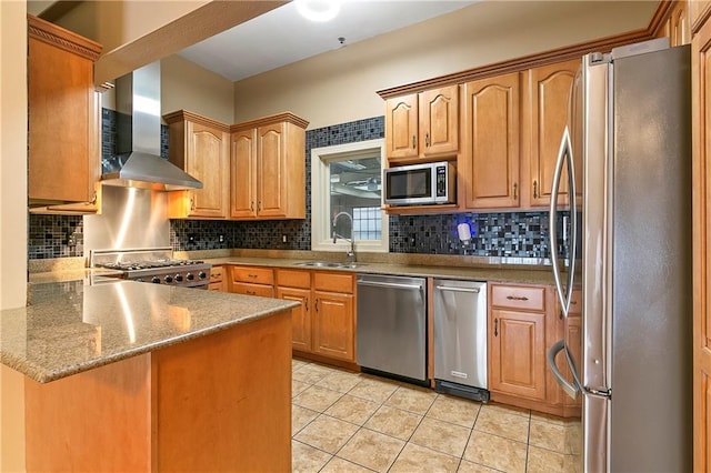 kitchen featuring kitchen peninsula, wall chimney range hood, light tile patterned floors, appliances with stainless steel finishes, and sink