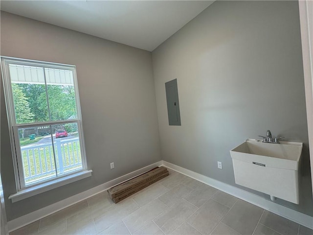 empty room featuring light tile patterned floors, electric panel, baseboards, and a healthy amount of sunlight