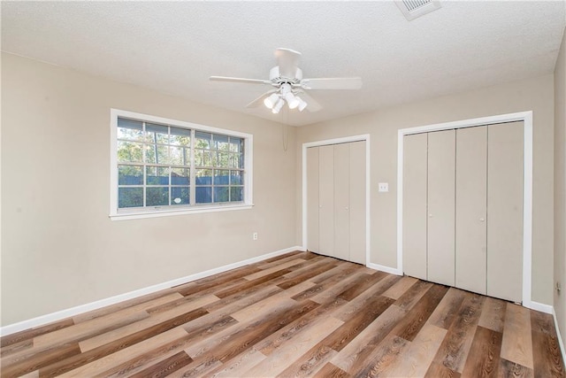 20 Silman Ave, Hammond, LA 70403 - unfurnished bedroom featuring two closets, wood finished floors, baseboards, a textured ceiling, and ceiling fan