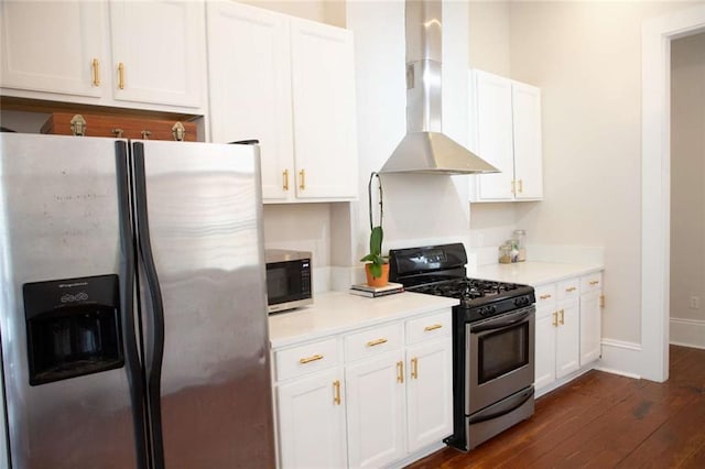 kitchen with appliances with stainless steel finishes, white cabinetry, wall chimney range hood, and dark hardwood / wood-style flooring