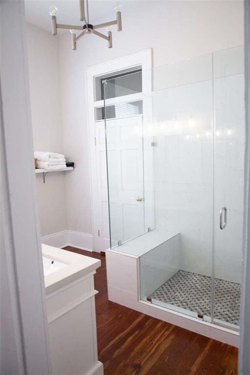 bathroom with vanity, hardwood / wood-style floors, a shower with shower door, and an inviting chandelier