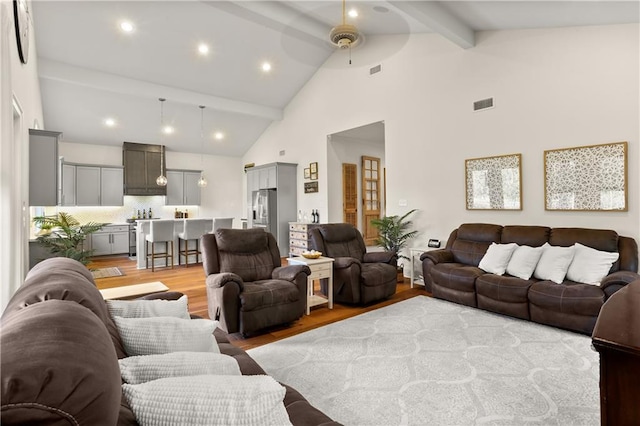 living room with beamed ceiling, light hardwood / wood-style flooring, high vaulted ceiling, and ceiling fan