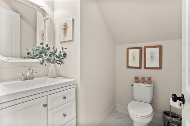 bathroom with toilet, lofted ceiling, and vanity