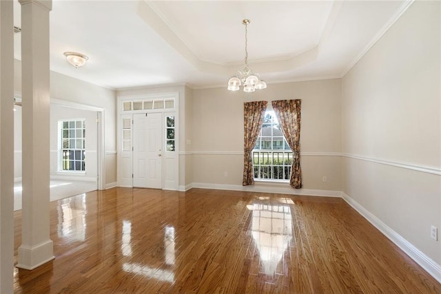 entrance foyer featuring wood-type flooring, ornamental molding, and a chandelier