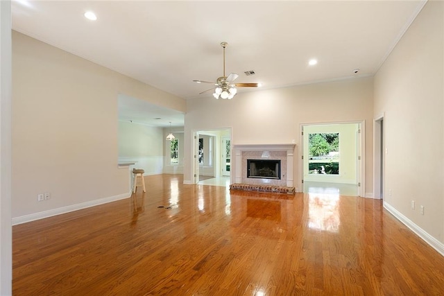 unfurnished living room with crown molding, wood-type flooring, and ceiling fan