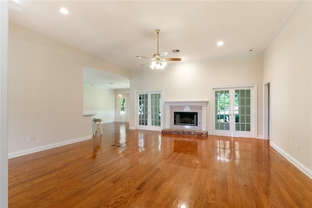 unfurnished living room featuring french doors, crown molding, ceiling fan, and hardwood / wood-style floors