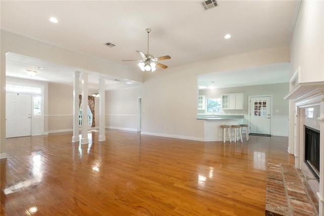 unfurnished living room featuring a wealth of natural light, ornamental molding, a brick fireplace, and light hardwood / wood-style floors