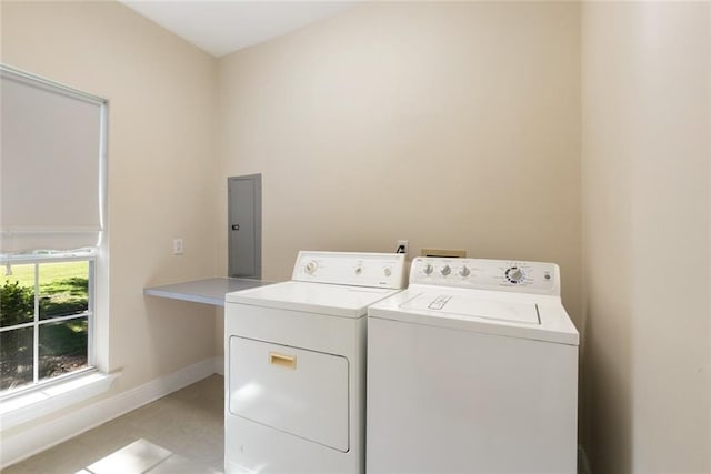 laundry area featuring electric panel, washing machine and dryer, and light tile patterned floors