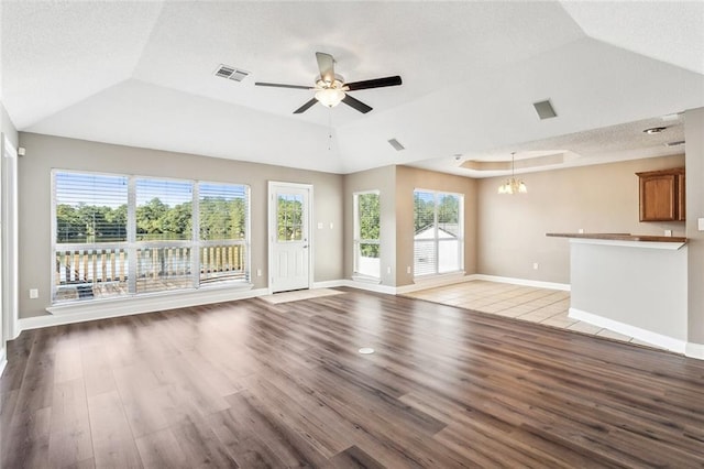 unfurnished living room featuring light hardwood / wood-style floors, a textured ceiling, lofted ceiling, and ceiling fan with notable chandelier