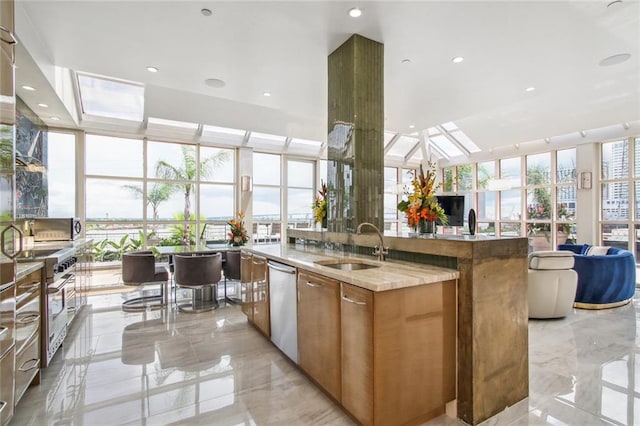 kitchen with light stone counters, a spacious island, sink, a skylight, and stainless steel appliances