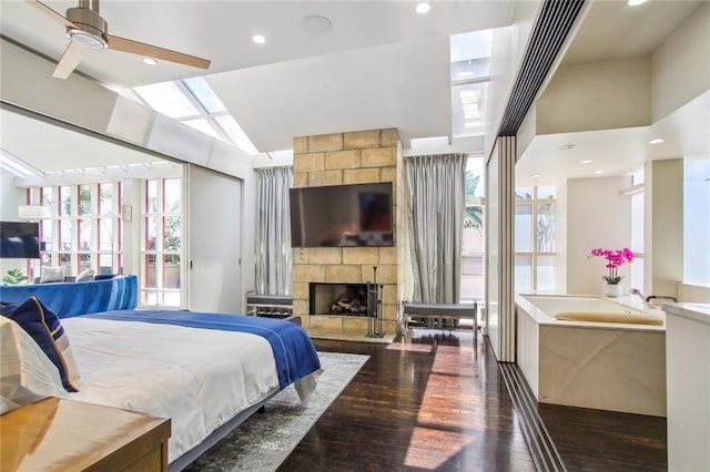 bedroom with dark wood-type flooring, ceiling fan, multiple windows, and a fireplace