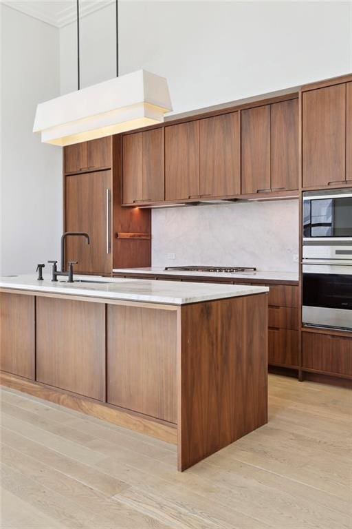 kitchen featuring backsplash, sink, stainless steel appliances, and light wood-type flooring