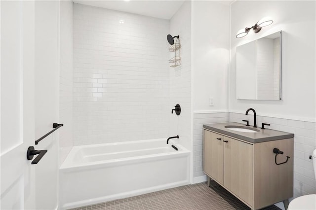 full bathroom with tile patterned floors, toilet, tiled shower / bath, tile walls, and vanity