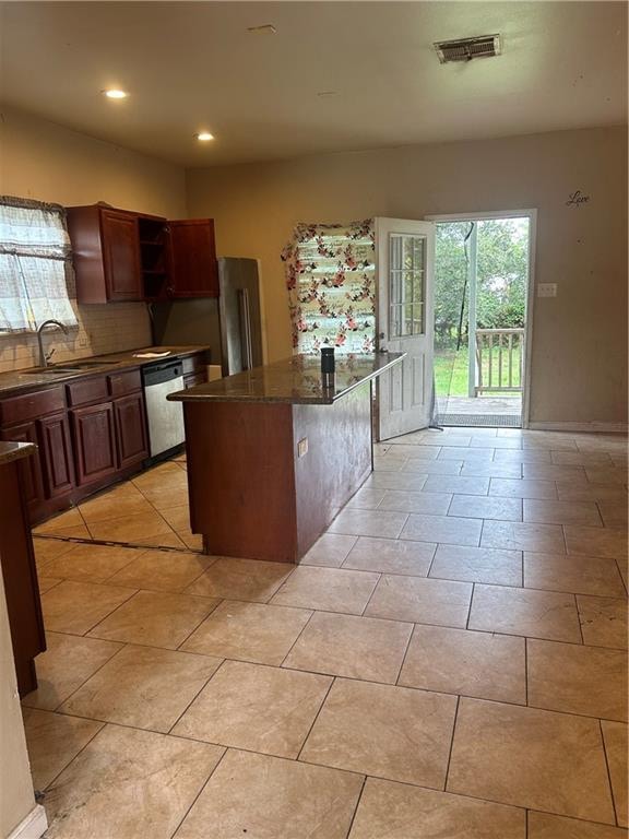 kitchen featuring decorative backsplash, a kitchen breakfast bar, dishwasher, sink, and a center island