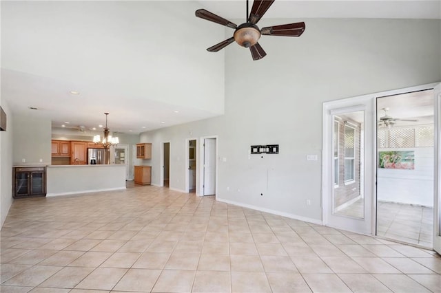 unfurnished living room with ceiling fan with notable chandelier, a high ceiling, and light tile patterned floors